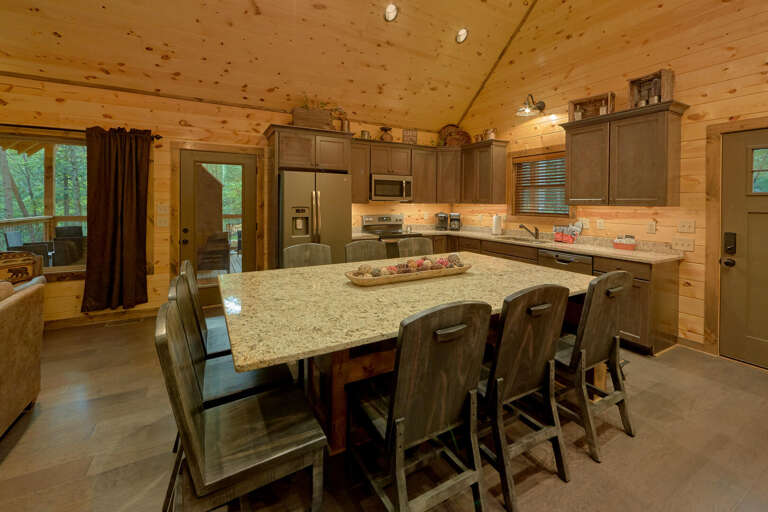 Wood-paneled Kitchen With Granite Table, Steel Stools, Surrounded By Serene Scene