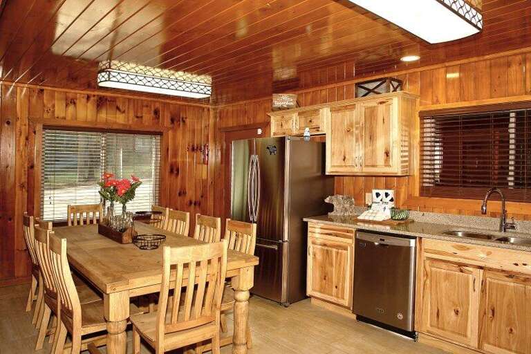 Wood-lined Kitchen With Wooden Dining Set And Stainless Steel Appliances