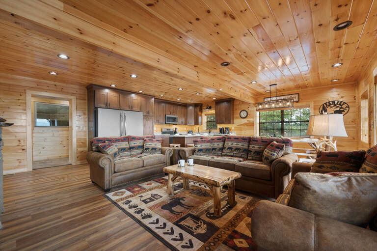 Spacious Living Area With Wooden Walls, Patterned Rugs, And Plush Sofas