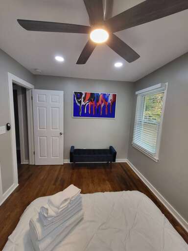 Interior Room With Bed, Sofa, Artwork, Ceiling Fan, And Doors
