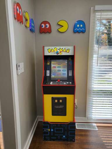 Pac-Man Arcade Machine In Room With Character Decorations On Wall