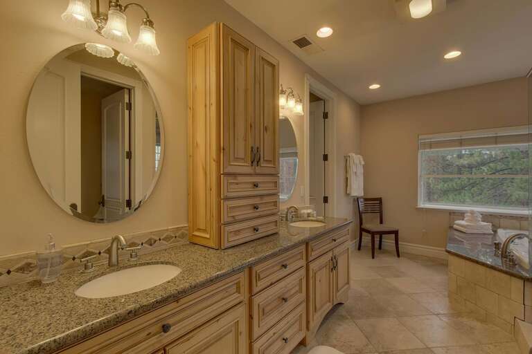 Bathroom with dual sinks, jetted tub, and glass enclosed shower