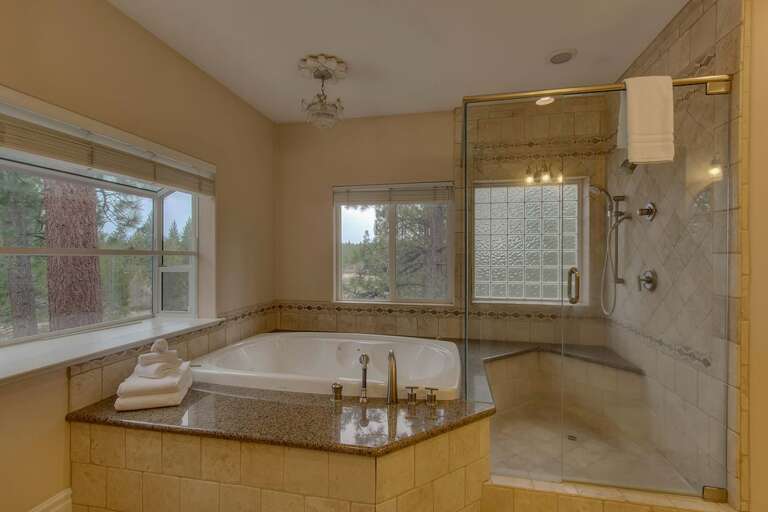 Bathroom with dual sinks, jetted tub, and glass enclosed shower