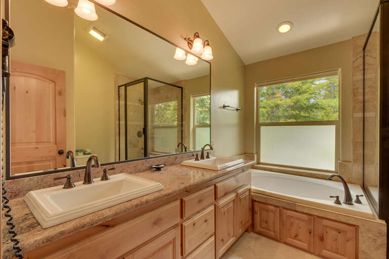 Bathroom with dual sinks, jetted tub, and glass enclosed shower