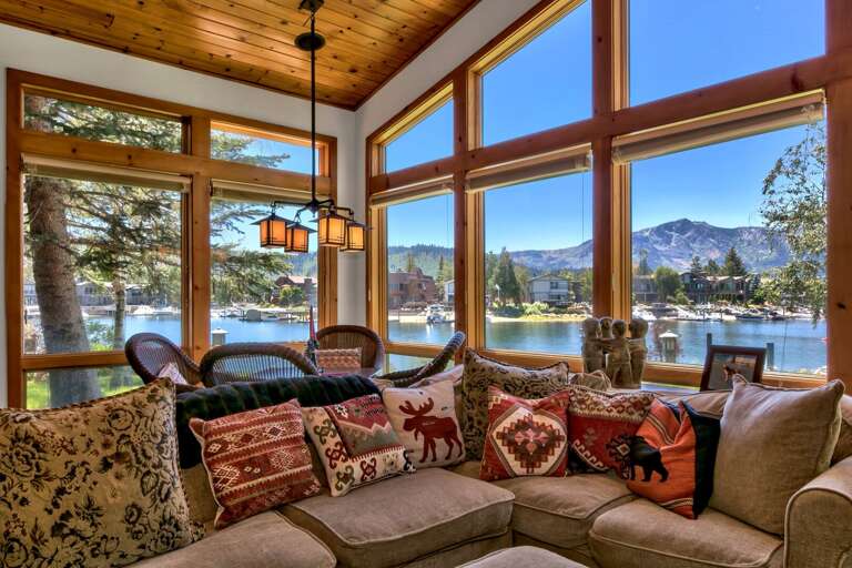 Living area with comfy sofa, flat screen tv, stone encased fireplace, and amazing view of  the lake