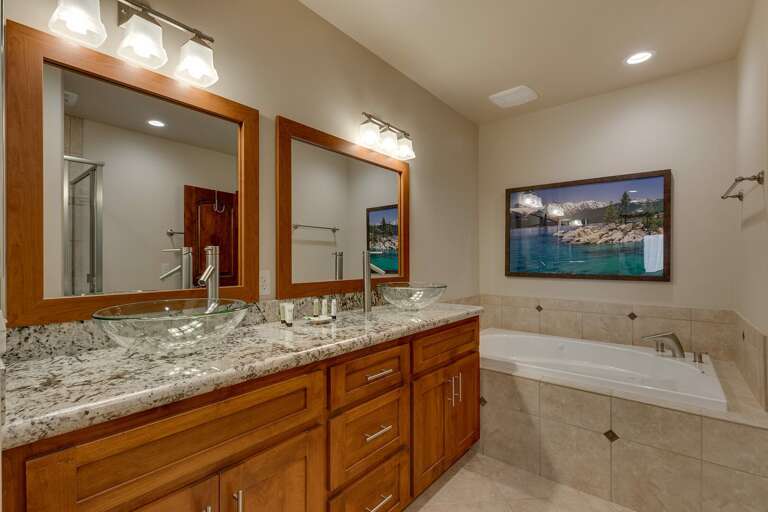 Bathroom with dual sinks, jetted tub, and glass enclosed shower