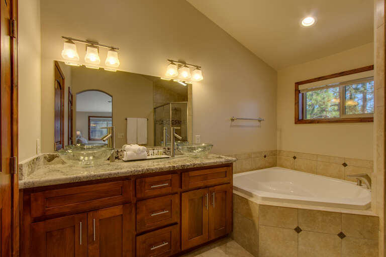 Bathroom with dual sinks, jetted tub, and glass enclosed shower