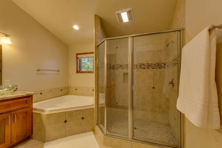 Bathroom with dual sinks, jetted tub, and glass enclosed shower