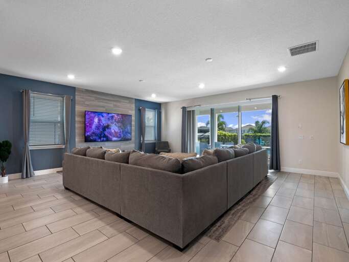 Living area with comfy sectional sofa, flat screen TV, and sliding doors to lanai and pool area Living area with comfy sectional sofa, flat screen TV, and sliding doors to lanai and pool area