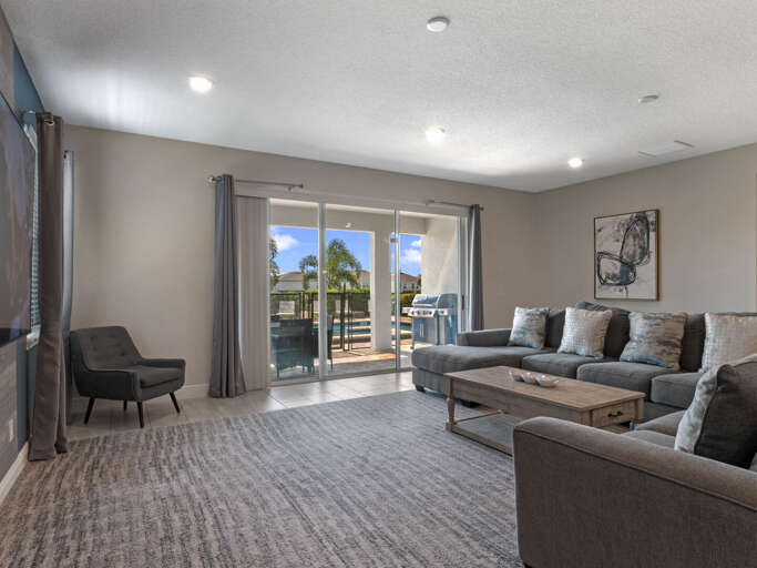 Living area with comfy sectional sofa, flat screen TV, and sliding doors to lanai and pool area Living area with comfy sectional sofa, flat screen TV, and sliding doors to lanai and pool area