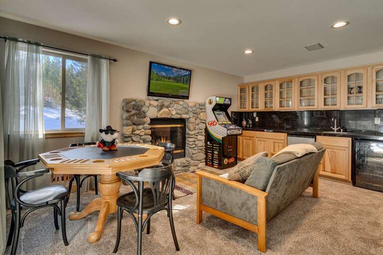 Lower level living area with comfy couch, adjacent dining, fireplace, mounted flat screen TV, arcades