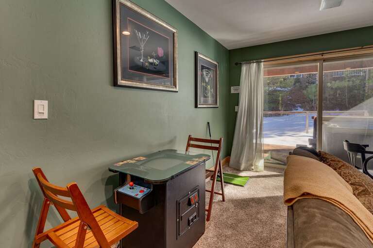 Lower level living area with comfy couch, adjacent dining, fireplace, mounted flat screen TV, arcades