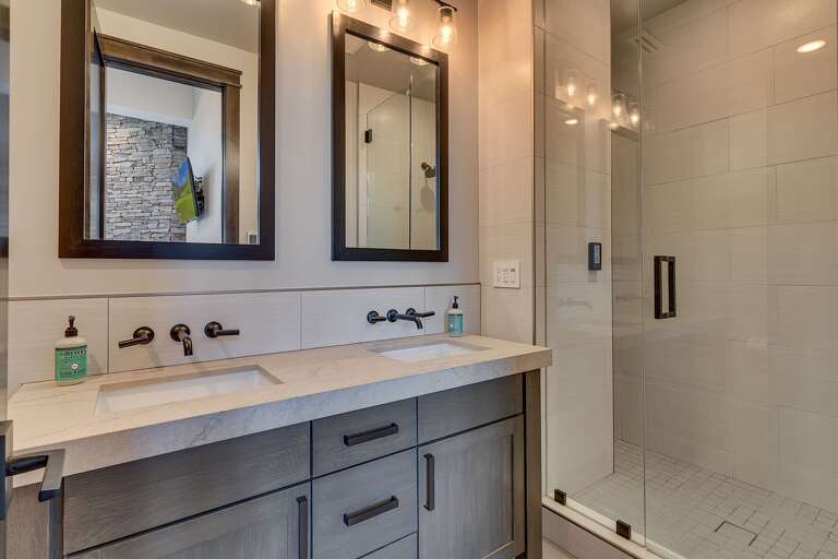 Bathroom with dual sinks and glass enclosed shower