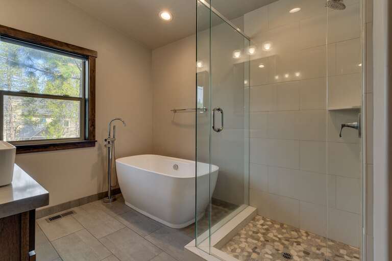 Bathroom w/ dual sinks, tub, and glass enclosed shower