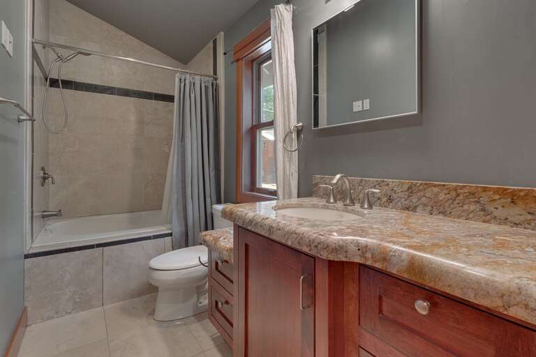 - Full upstairs bathroom with shower and tub combination
- Spacious vanity with granite countertops and ample storage
- Modern tiled bathroom conveniently located near upstairs bedrooms