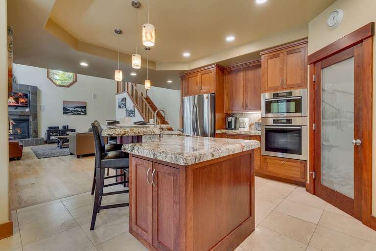 - Gourmet kitchen with granite countertops and island seating
- Open-concept layout overlooking the great room
- Tahoe vacation rental with warm wood finishes throughout
