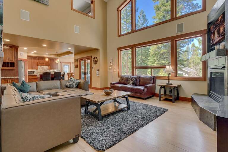 - Spacious great room with soaring windows and forest views
- Cozy living area with fireplace and plush seating
- Tahoe vacation rental with open-concept design