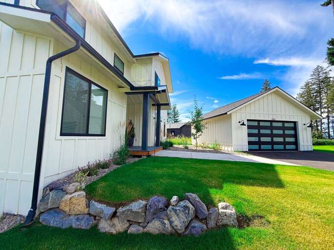White Walled Vacation Rental With Vibrant Green Grass And Garage