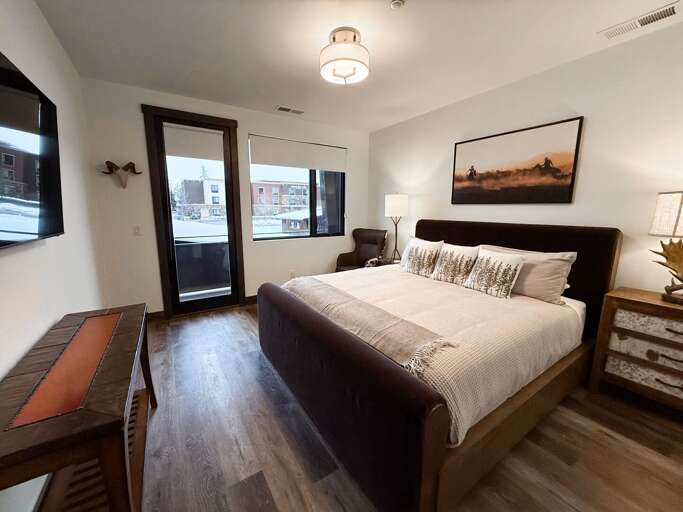 Bedroom With Balcony, Bed And Desk, Bright Walls And Wooden Floor