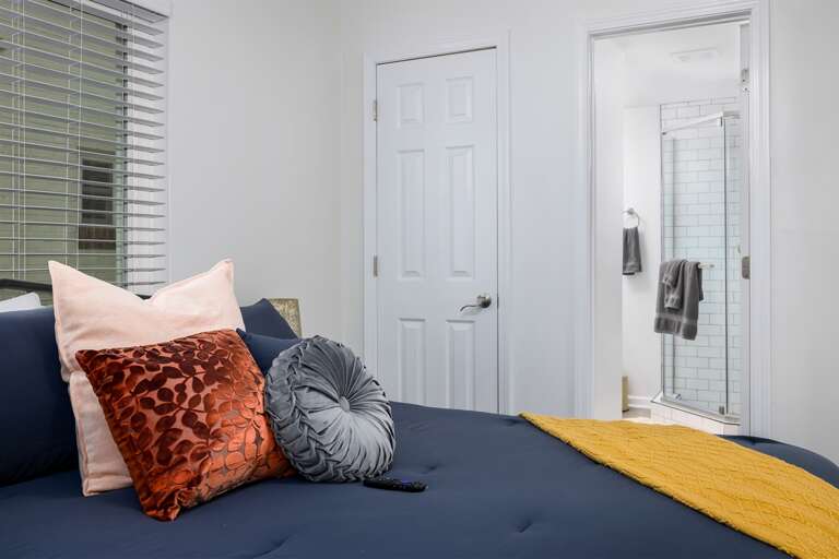 Modern Bedroom Interior With Decorative Pillows And Adjacent Bathroom