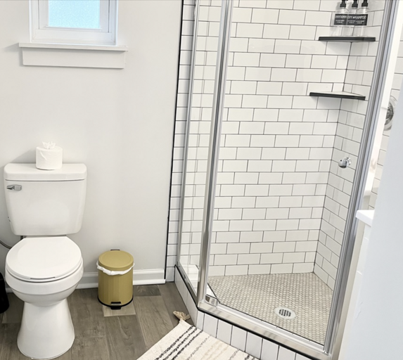 Modern Bathroom With White Subway Tiles, Glass Shower, And Toilet