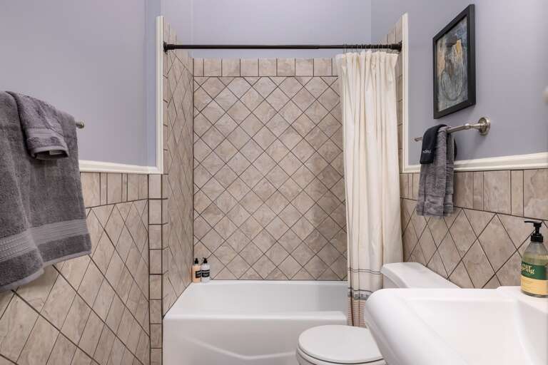 The hallway bathroom features a versatile tub-shower combination, providing flexibility for a relaxing soak or a quick and convenient shower.