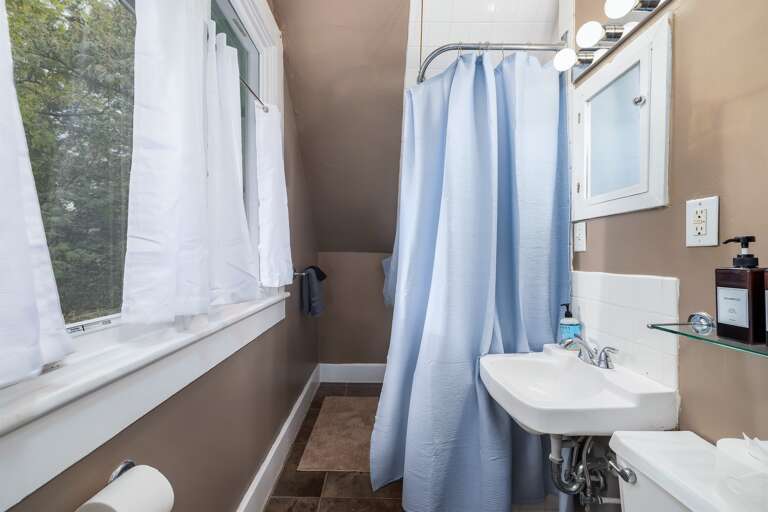 The queen bedroom upstairs features a full en-suite bathroom with a convenient shower-tub combo for your comfort. The queen bedroom upstairs features a full en-suite bathroom with a convenient shower-tub combo for your comfort.