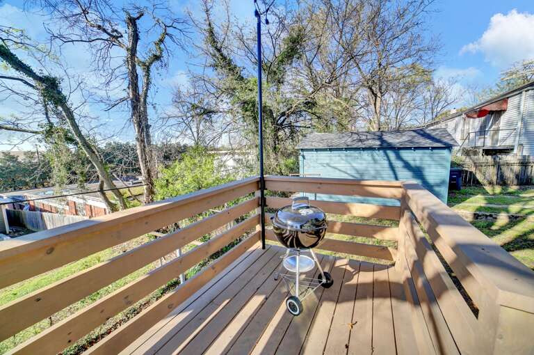 **Grilling Made Easy**: The charcoal grill on the porch invites guests to enjoy outdoor cooking amidst the bungalow's charming setting.