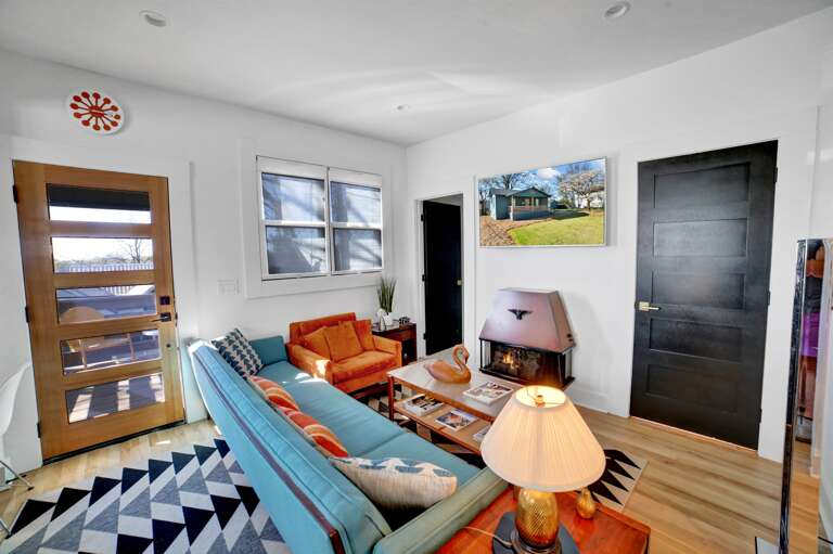 **Living Room Elegance**: The living room radiates warmth with a cozy fireplace and flatscreen TV, complemented by comfortable seating including a snug couch and a generous armchair.