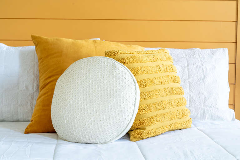 Add a splash of joy to your rest with these vibrant yellow pillows in our queen suite, blending comfort with a burst of sunshine.