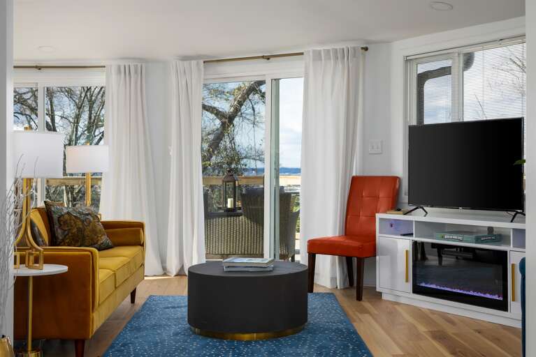 Vibrant hues set the mood in a room featuring a smart TV and a chic faux fireplace, combining fun, technology, and coziness. Making your stay the best home away from home.   Get in touch to explore our custom concierge services and local experiences.