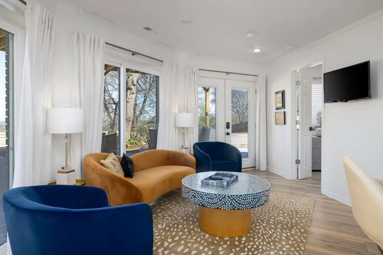 Immerse yourself in a space where elegance and comfort converge, featuring a high-tech viewing setup, inviting couches, and refined drapery, setting the scene for relaxation and entertainment.