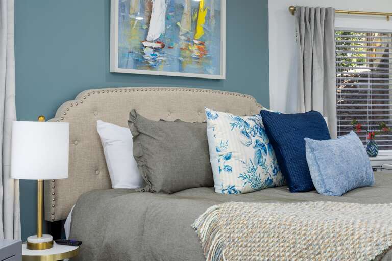 Discover serenity in the king suite, bathed in beautiful blue hues that calm the mind, complemented by a beautiful artwork, abundant storage, and snug linens for ultimate comfort.