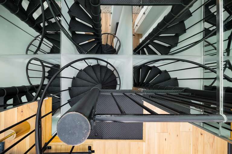 An iron spiral staircase winds gracefully down, offering an elegant path to the lower level and adding a touch of sophistication. Message us about our concierge services and locally curated experiences. 