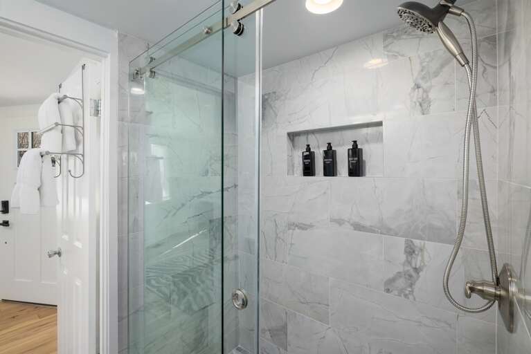 **Spa-Like Serenity**: Experience spa-like serenity with plush white linens and premium toiletries, including shampoo, conditioner, and body wash, set against a backdrop of sleek marble.