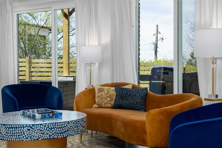 Indulge in the living room's comforts, from the smart TV offering endless entertainment to the cozy seating beneath luxurious white curtains, crafting a haven of rest and leisure.