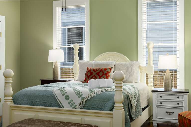 This cozy bedroom features a comfortable queen-sized bed adorned with soft linens and decorative pillows. The room is tastefully decorated, offering a serene and inviting atmosphere. A smart TV ensures entertainment is just a click away.