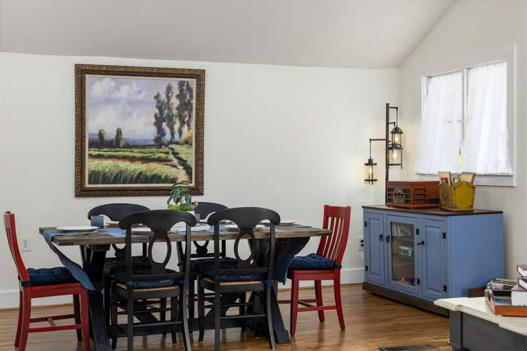 The elegant dining area boasts a stylish table set for six, creating a perfect spot for family meals or intimate dinners with friends. The space is beautifully lit and decorated, contributing to the home's inviting atmosphere.