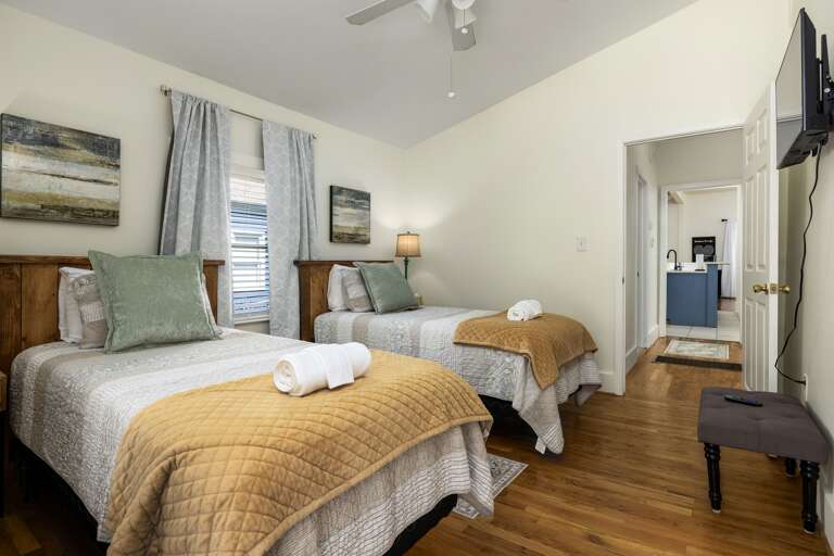This bright and airy bedroom features two twin beds and a smart TV. It's a perfect space for children or additional guests, offering comfort and entertainment. 