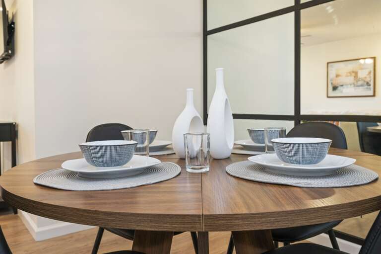 Dine comfortably at the table for four, enhanced by a chic mirrored wall that adds space and elegance to your culinary adventures.