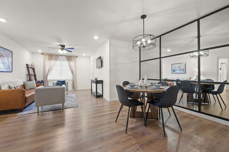 The living room with a smart TV invites relaxation, seamlessly flowing into a modern kitchen complete with stainless appliances. Adjacent is a chic dining area and a stylish workspace, perfect for dining and productivity.