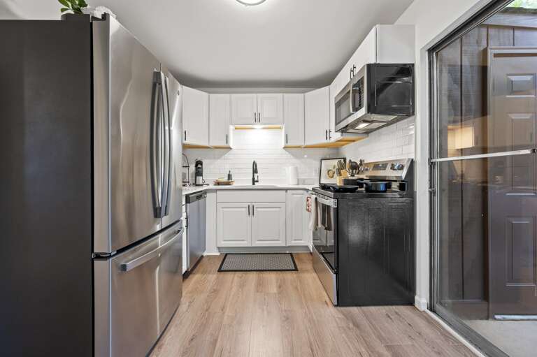 The cozy living room, filled with plush seating and vibrant artwork, seamlessly transitions into a modern kitchen featuring sleek countertops and stainless steel appliances. From there, step onto the inviting patio, perfect for relaxing or dining al fresc