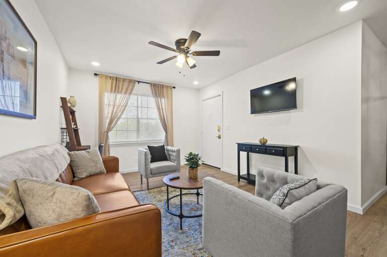 Cozy and inviting living room with plush seating and large windows offering abundant natural light. Decorated in soft neutral tones with stylish accents, the space is perfect for relaxation or enjoying a good book.