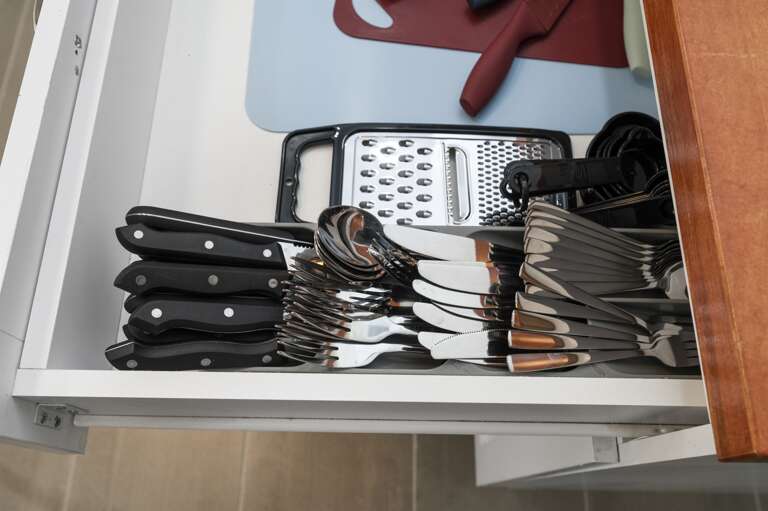 Kitchen prepared for your stay with silverware and cutting boards, ready for meal prep.