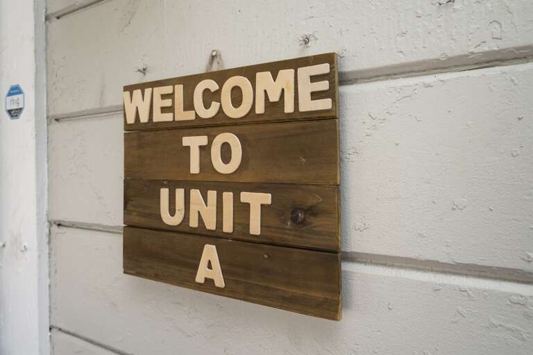 A wooden sign with the words "Welcome to Unit A" is affixed to a softly hued wall, inviting guests into your home away from home.  A wooden sign with the words "Welcome to Unit A" is affixed to a softly hued wall, inviting guests into your home away from home.