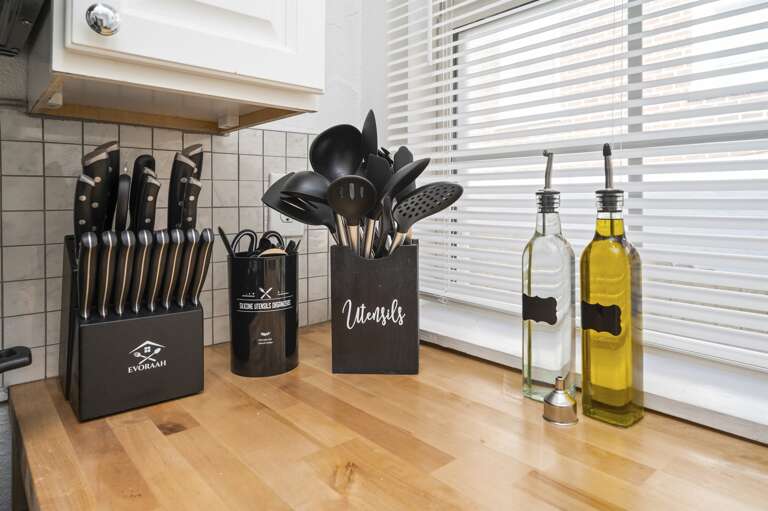 Kitchen stocked with utensils, knives, and cooking oil, ready for meal preparation.