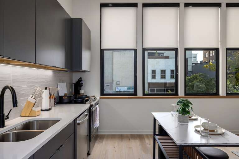 Cook with a view—this sleek kitchen offers not only modern amenities but also a stunning cityscape through large windows, adding inspiration to your culinary creations and daily routines.