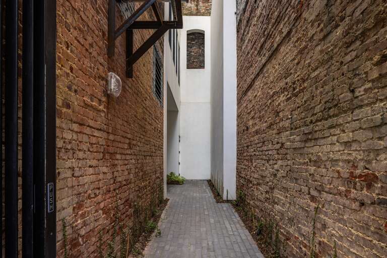 Historic pathway—the charming brick corridor, with its exposed textures, leads guests to the main building, blending historic character with modern design for an unforgettable entrance.