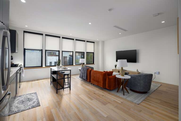 Open-concept living—this spacious living area features floor-to-ceiling windows for natural light, a plush sofa for ultimate relaxation, and a fully equipped kitchen for culinary freedom.