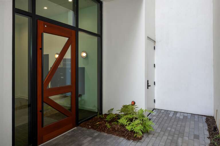 An inviting welcome—the modern, wood-framed glass entrance offers both security and style, setting the tone for the contemporary comforts waiting inside.